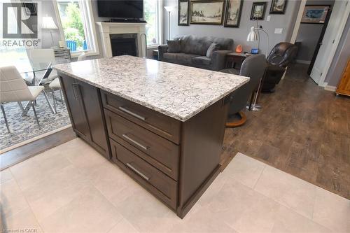 Kitchen island featuring a light-toned countertop and rich wood-finish cabinetry with brushed nickel hardware - 10 Craddock Boulevard, Jarvis, ON - Indoor With Fireplace