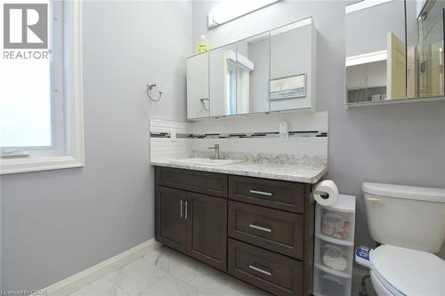 Modern bathroom featuring a dark wood vanity with dual sinks, white quartz countertop with integrated backsplash, and polished chrome fixtures - 10 Craddock Boulevard, Jarvis, ON - Indoor Photo Showing Bathroom