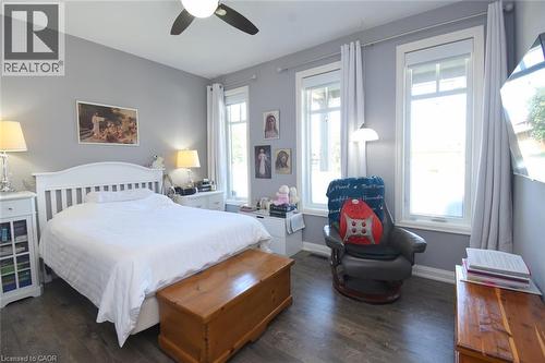 Bright, light-filled bedroom featuring a white wooden bed frame, hardwood flooring, and multiple large windows with sheer curtains - 10 Craddock Boulevard, Jarvis, ON - Indoor Photo Showing Bedroom