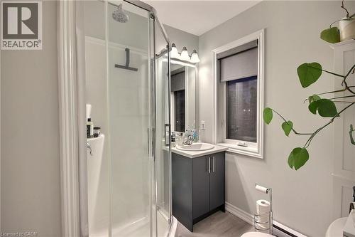 Modern ensuite bathroom featuring a frameless glass shower enclosure with chrome fixtures, a dark vanity with integrated sink and contemporary hardware, LED-illuminated mirror, and neutral tile floori - 287 Chapel Hill Drive, Kitchener, ON - Indoor Photo Showing Bathroom