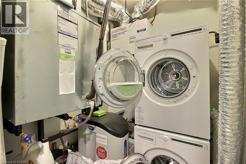 Laundry area featuring a stacked washer and dryer, water softener system, and HVAC unit with visible ductwork - 287 Chapel Hill Drive, Kitchener, ON - Indoor Photo Showing Laundry Room