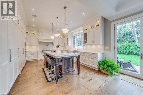Gourmet kitchen featuring a large central island with seating, white shaker cabinetry, light wood-finish flooring, recessed lighting, and direct access to an exterior patio - 436 Willis Drive, Oakville, ON - Indoor Photo Showing Kitchen With Upgraded Kitchen