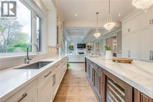 Gourmet kitchen featuring a large central island with integrated beverage refrigerator, white perimeter cabinetry with under-cabinet lighting, stainless steel undermount sink with gooseneck faucet, an - 436 Willis Drive, Oakville, ON - Indoor Photo Showing Kitchen With Upgraded Kitchen