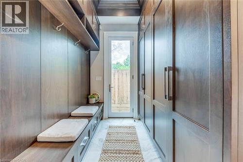 Mudroom featuring built-in wood-finish cabinetry, integrated seating with storage drawers, wall-mounted coat hooks, and a glass-paneled exterior door - 436 Willis Drive, Oakville, ON -  Photo Showing Other Room