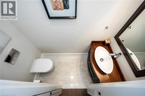 Modern powder room featuring a curved wood-finish vanity with an oval vessel sink, a wall-mounted faucet, and a large framed mirror - 436 Willis Drive, Oakville, ON - Indoor Photo Showing Bathroom