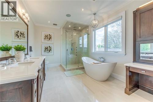 Expansive bathroom featuring light-toned flooring, a freestanding soaking tub, a glass-enclosed shower, a dual vanity with a light-toned countertop and dark wood cabinetry, and a large window - 436 Willis Drive, Oakville, ON - Indoor Photo Showing Bathroom