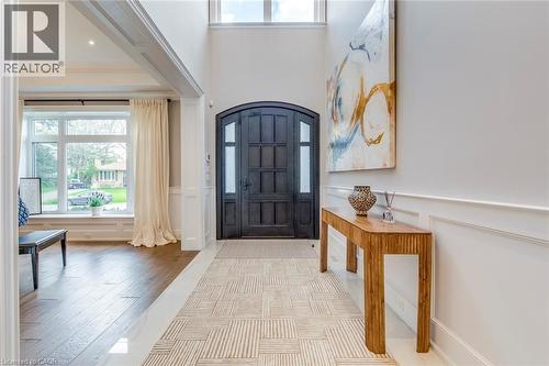 Grand entryway featuring a dark wood double door, a two-story ceiling, wainscoting, and wood-finish flooring - 436 Willis Drive, Oakville, ON - Indoor Photo Showing Other Room