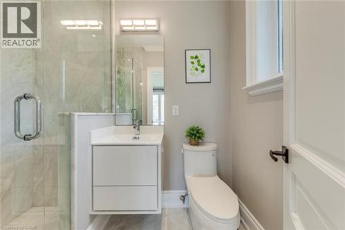 Bathroom featuring a frameless glass shower enclosure, a wall-mounted vanity with integrated sink, contemporary lighting fixtures, a window with trim, and a white paneled door with dark hardware - 436 Willis Drive, Oakville, ON - Indoor Photo Showing Bathroom