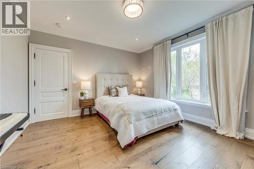 Bedroom featuring wood-finish flooring, a large window with white trim, a decorative ceiling light fixture, recessed lighting, and a solid white interior door - 436 Willis Drive, Oakville, ON - Indoor Photo Showing Bedroom