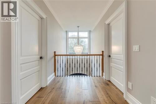Upper-level hallway featuring hardwood flooring, crown molding, white panel doors, and a wrought iron and wood handrail - 436 Willis Drive, Oakville, ON - Indoor Photo Showing Other Room