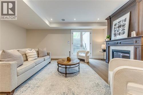 Recessed lighting illuminates the open living space featuring wood-finish flooring, a detailed fireplace with a stone surround, and light-toned walls - 436 Willis Drive, Oakville, ON - Indoor Photo Showing Living Room With Fireplace