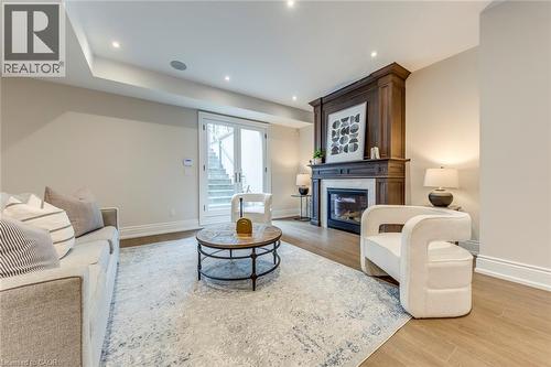 Living area featuring a grand wood-paneled fireplace surround with a white marble hearth, recessed lighting, and wood-finish flooring - 436 Willis Drive, Oakville, ON - Indoor Photo Showing Living Room With Fireplace
