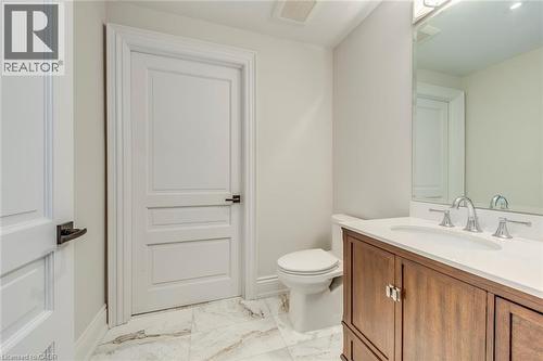 Bathroom featuring a wood-finish vanity with a white countertop and undermount sink, wall-mounted mirror, and tile flooring - 436 Willis Drive, Oakville, ON - Indoor Photo Showing Bathroom