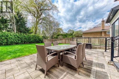 Expansive backyard featuring a paver patio, lush green lawn, mature trees, and privacy hedging - 436 Willis Drive, Oakville, ON - Outdoor With Deck Patio Veranda With Exterior