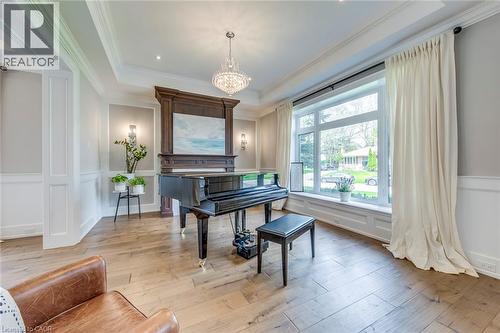 Spacious room featuring wide plank wood-finish flooring, an ornate chandelier, a large picture window, wainscoting, and crown molding - 436 Willis Drive, Oakville, ON - Indoor