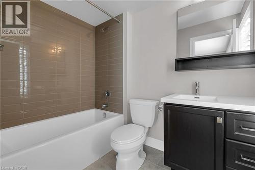 Bathroom featuring a white bathtub with subway tile surround, polished chrome fixtures, a dark wood-finish vanity with an integrated sink, and a framed mirror - 2 Waterview Lane, Grimsby, ON - Indoor Photo Showing Bathroom