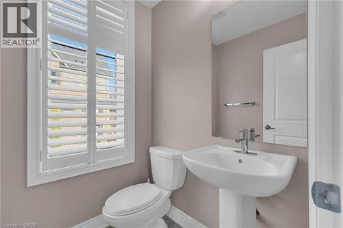 Pedestal sink with chrome faucet, a white toilet, and window with plantation shutters - 2 Waterview Lane, Grimsby, ON - Indoor Photo Showing Bathroom