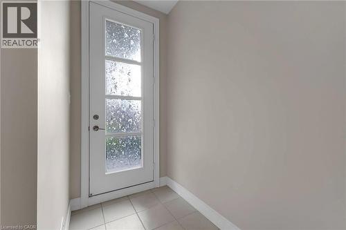 White door with four frosted glass panels and brushed nickel hardware, set against light neutral walls and light-toned tile flooring - 2 Waterview Lane, Grimsby, ON - Indoor Photo Showing Other Room