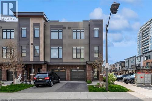 Contemporary townhouse exterior featuring a multi-tone facade with dark siding, tan panels, and brick accents - 2 Waterview Lane, Grimsby, ON - Outdoor With Facade
