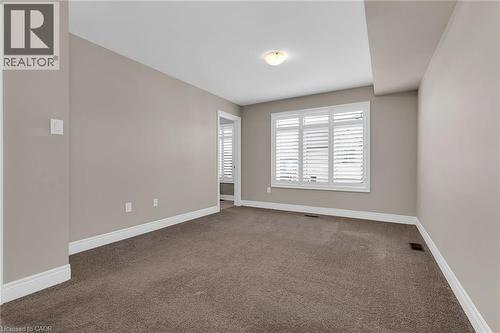 Carpeted interior space with a window featuring white plantation shutters and a ceiling-mounted light fixture - 2 Waterview Lane, Grimsby, ON - Indoor Photo Showing Other Room