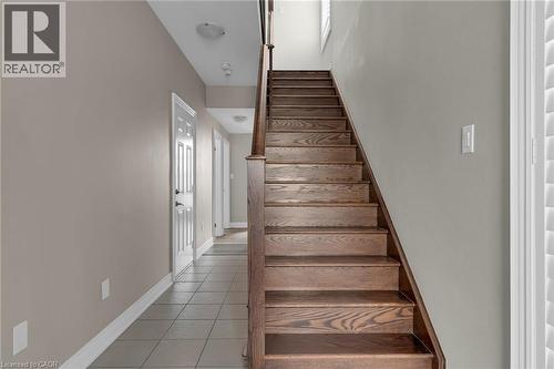 Hardwood staircase featuring wood balusters, light gray wall tones, tile flooring, and white trim - 2 Waterview Lane, Grimsby, ON - Indoor Photo Showing Other Room