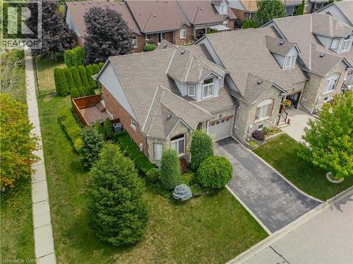 Stone and brick exterior residence featuring a front-facing garage, dormer windows, and a paved driveway - 24 Knack Lane, Cambridge, ON - Outdoor