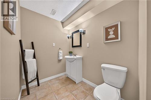 Neutral-toned bathroom featuring a white toilet, a vanity with a white basin and cabinet storage, and an overhead light fixture - 24 Knack Lane, Cambridge, ON - Indoor Photo Showing Bathroom
