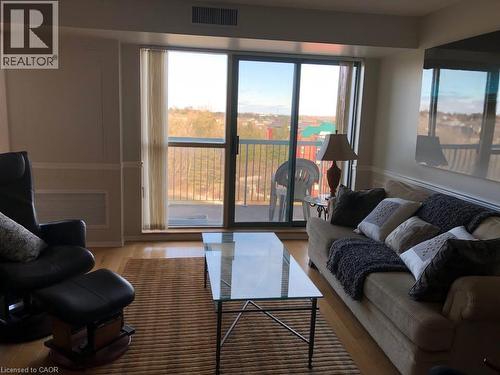 Living area featuring wood-finish flooring, a full-height sliding glass door leading to a balcony, and a recessed ceiling air vent - 30 Blue Springs Drive Unit# Ph3, Waterloo, ON - Indoor Photo Showing Living Room