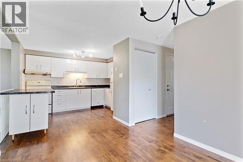 Kitchen with white cabinetry, dark speckled countertops, and wood-finish flooring - 129 Kovac Road, Cambridge, ON - Indoor Photo Showing Kitchen