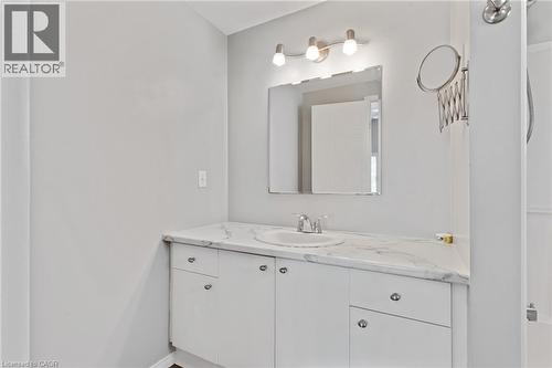 White vanity with a single basin sink and a stone-finish countertop - 129 Kovac Road, Cambridge, ON - Indoor Photo Showing Bathroom