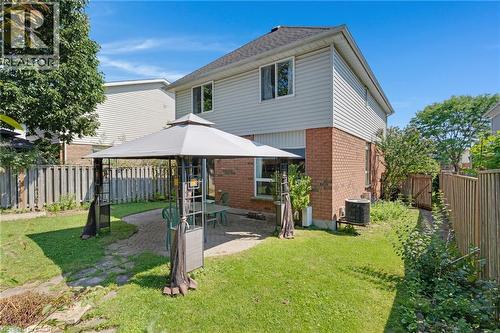 Spacious rear yard featuring a brick and siding exterior, multiple windows, a paved patio area, and a privacy fence - 129 Kovac Road, Cambridge, ON - Outdoor With Exterior