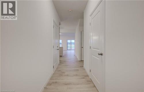 Hallway featuring light wood-finish flooring, white paneled doors with brushed nickel hardware, and neutral wall tones - 89 Rivergreen Crescent, Cambridge, ON - Indoor Photo Showing Other Room