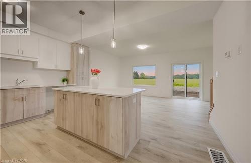 Open-concept living space featuring light wood-finish flooring, white walls, and a modern kitchen island with a light-toned countertop - 89 Rivergreen Crescent, Cambridge, ON - Indoor Photo Showing Kitchen