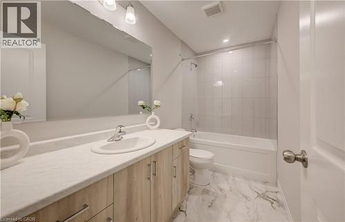 Bathroom featuring a wood-finish vanity with a light-toned countertop, an integrated sink, and a large wall-mounted mirror - 89 Rivergreen Crescent, Cambridge, ON - Indoor Photo Showing Bathroom