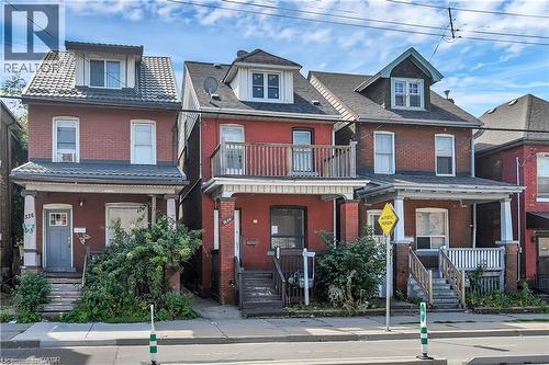 Brick exterior featuring a covered front porch with columns and a gray door - 334 Cannon Street E, Hamilton, ON - Outdoor With Balcony With Facade
