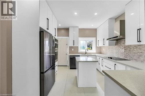 Modern galley kitchen featuring white cabinetry with integrated hardware, quartz countertops, and a mosaic tile backsplash - 334 Cannon Street E, Hamilton, ON - Indoor Photo Showing Kitchen With Upgraded Kitchen