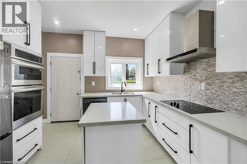 Contemporary kitchen featuring white cabinetry with matte black hardware, light-toned countertops, a multi-tone tile backsplash, and stainless steel appliances - 334 Cannon Street E, Hamilton, ON - Indoor Photo Showing Kitchen With Double Sink With Upgraded Kitchen