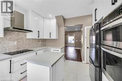 Modern kitchen with white cabinetry, light-toned countertops, and a full stainless steel appliance suite including double ovens - 