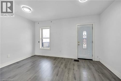 Entryway featuring a decorative glass panel door, grey wood-finish flooring, white baseboards, and two modern flush-mount ceiling lights - 334 Cannon Street E, Hamilton, ON - Indoor Photo Showing Other Room