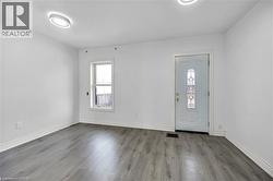 Entryway featuring a decorative glass panel door, grey wood-finish flooring, white baseboards, and two modern flush-mount ceiling lights - 
