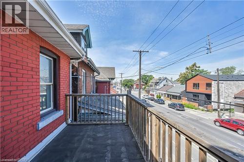 Exterior balcony featuring a wood railing and a flat surface, offering an open-air extension from the red brick facade - 334 Cannon Street E, Hamilton, ON - Outdoor With Balcony With Exterior