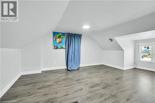 Spacious room featuring sloped ceilings, light gray wood-finish flooring, white baseboards, and a circular ceiling light fixture - 334 Cannon Street E, Hamilton, ON - Indoor Photo Showing Other Room