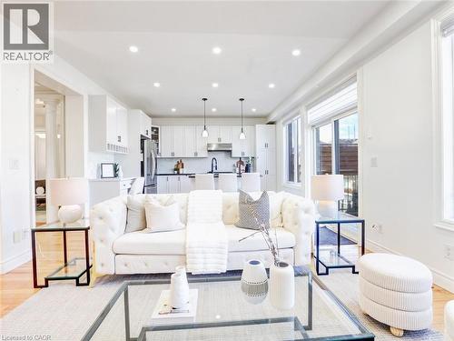 Open-concept living area featuring wood-finish flooring, recessed lighting, and a kitchen with white cabinetry - 584 Pinery Trail, Waterloo, ON - Indoor Photo Showing Other Room