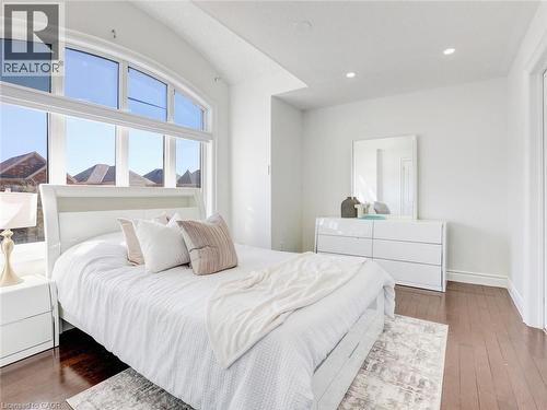 Expansive arched window with multiple panes, recessed lighting, white walls, dark wood-finish flooring, and white trim throughout - 584 Pinery Trail, Waterloo, ON - Indoor Photo Showing Bedroom