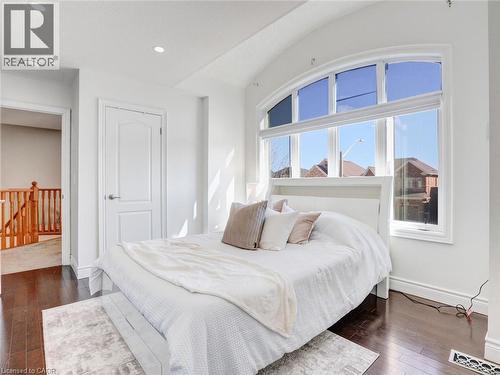 Bright bedroom featuring an arched window, dark wood-finish flooring, recessed lighting, white baseboards, and a white interior door - 584 Pinery Trail, Waterloo, ON - Indoor Photo Showing Bedroom