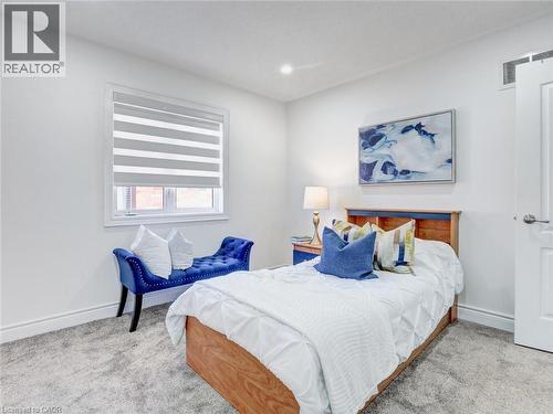 Bright bedroom with a window featuring horizontal blinds, recessed ceiling lighting, light grey carpeting, and white baseboards - 584 Pinery Trail, Waterloo, ON - Indoor Photo Showing Bedroom