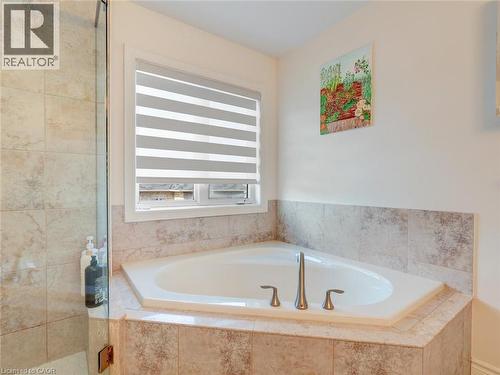 Corner soaking tub with deck-mounted brushed nickel fixtures, surrounded by neutral-toned tile and a glass-enclosed shower - 584 Pinery Trail, Waterloo, ON - Indoor Photo Showing Bathroom