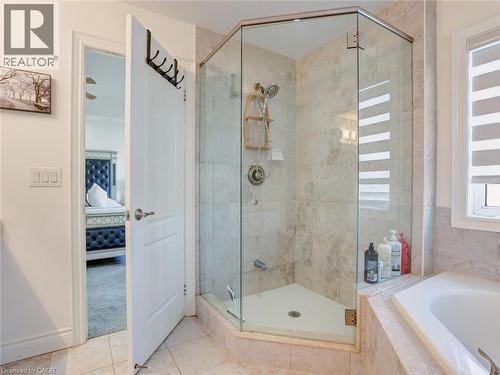 Glass-enclosed shower with stone-finish tile surround and a built-in corner bench - 584 Pinery Trail, Waterloo, ON - Indoor Photo Showing Bathroom