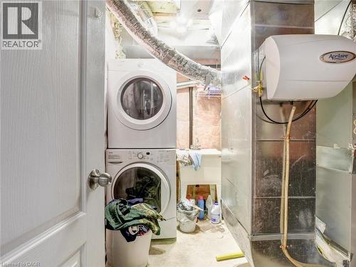 Dedicated laundry area featuring a stacked washer and dryer, utility sink, and visible ductwork - 584 Pinery Trail, Waterloo, ON - Indoor Photo Showing Laundry Room
