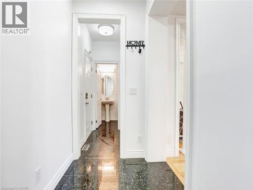 Hallway featuring dark, reflective floor tiling, white baseboards, and a white interior door with decorative glass inserts - 584 Pinery Trail, Waterloo, ON - Indoor Photo Showing Other Room